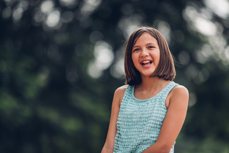 Portrait of a beautiful girl  in the bokeh of leaves is a green backdrop of nature, The girl smiled happily at the camera.の写真素材