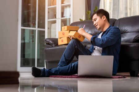 Online sales young start small business in a cardboard box at work. The seller prepares the delivery box for the customer, or ecommerce. Work from home concept.の写真素材