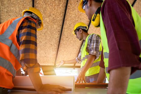 [Construction Teamwork ] Team of engineer and architects working, meeting, discussing,designing, planing, measuring layout of building blueprints in construction site floor at factory.の写真素材