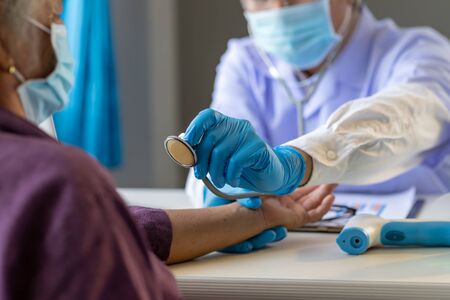 Asian doctor use stethoscope listening lung of patient, elderly health check up , they wear surgical mask the aging female patient that is at risk for infection corona virus [covid-19].の写真素材