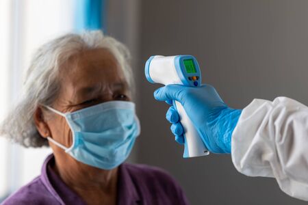 The coronavirus check post, Doctors checking temperature the aging female patient that is at risk for infection corona virus [covid-19].の写真素材