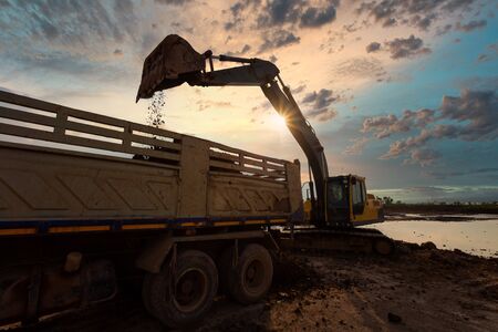 excavator at sandpit during earthmoving works ifilling a dump truck with rock and soil for fill at a new commercial development road construction projectの写真素材