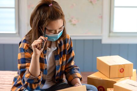 Asian women working sit and think about marketing analysis from home in room floor with postal parcel, Selling online ideas concept, new normal.の写真素材