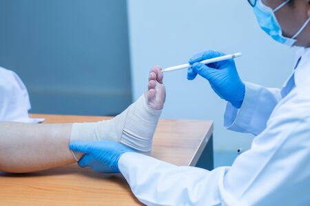 Close-up hand wear medical gloves doctor examines the leg of the womanâs heel for heel spurs, pain in the foot, plantar fasciitis, osteophyteの写真素材