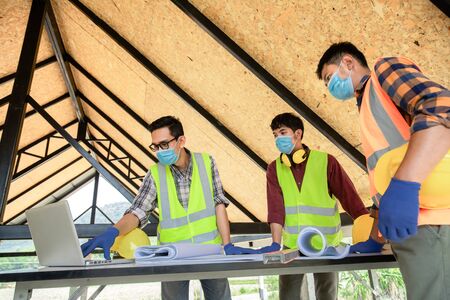 Team of construction engineers and three architects are ready to wear medical masks. Coronavirus or Covid-19 wear masks during the design of construction. New normalの写真素材