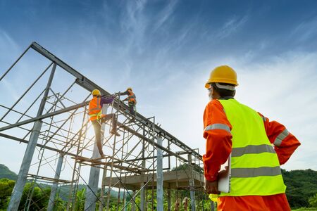 Engineer technician watching team of workers on high steel platform, Engineer technician construction worker control and Analyzing an Unfinished Construction project in construction site.の写真素材