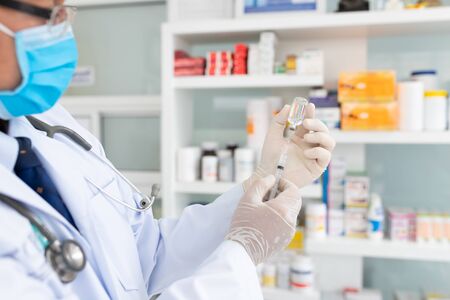 Hand of Doctor or nurse holding syringe and vaccine.researcher hand in gloves holding flu, coronavirus vaccine disease preparing for human clinical trials vaccination shot, medicine and drug concept.の写真素材