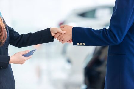 Asian auto business, car sale, deal, gesture and people concept - close up of dealer new owner and shaking hands in auto showroomの写真素材