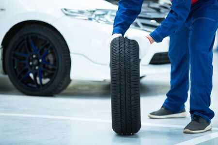 Asian mechanic in uniform is changing a wheels/tires while working in car repair centerの写真素材