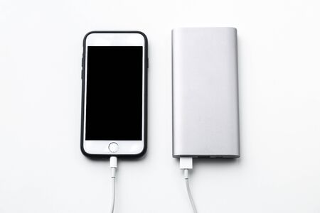 Smartphone charging with power bank on white background.