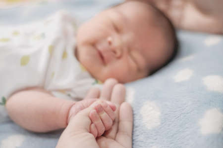 close-up hand the asian New born baby in the hand of mother.の写真素材