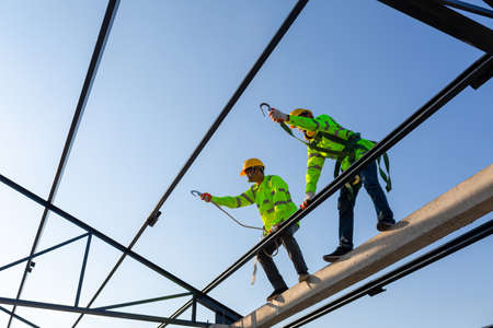 Asian worker wear safety height equipment to build a steel roof structure in the construction site.の写真素材