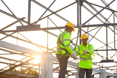 Asian worker wear safety equipment handing bricks to each other. Teamwork concept in the construction site.の写真素材