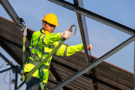 Asian roof construction worker wear safety height equipment to install the roof frame, Fall arrestor device for worker with hooks for safety body harness in the construction site.の写真素材