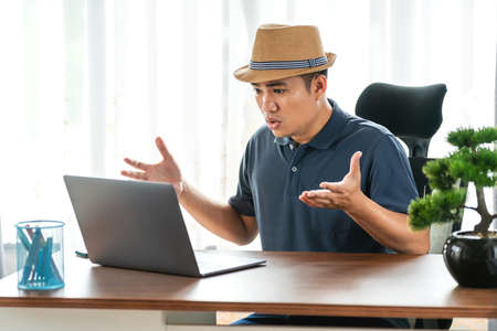 remote job, technology and people concept - stressed young asian man with laptop computer working at home, Concept of technology communicationの写真素材