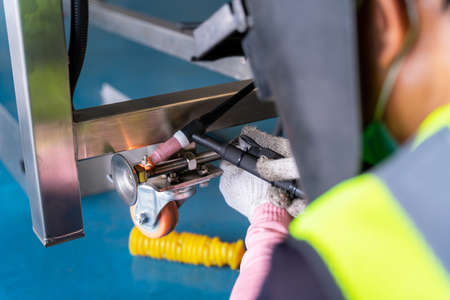 Worker welding aluminum construction a  piece of conveyer