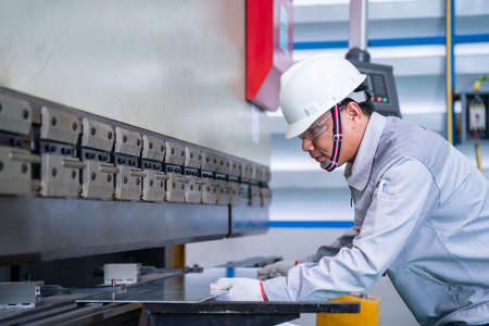 Asian technician worker wearing a safety suit and sheet Metal Bending in industrial factory, Safety first concept.の写真素材