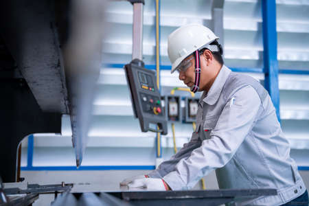 Asian technician worker wearing a safety suit and sheet Metal Bending in industrial factory, Safety first concept.の写真素材