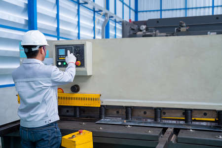 Asian worker wearing a safety suit and setting Hydraulic Press Break Machine and Prepared Sheet...