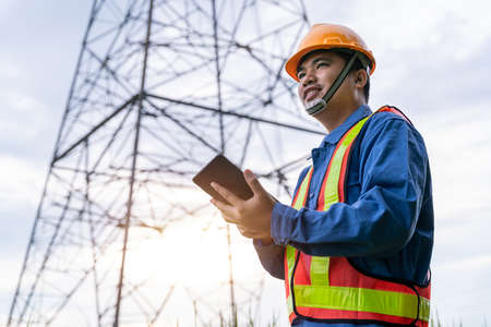 Picture of Asian engineering wear safety clothes working on High-voltage tower, Check the information on taplet.の写真素材