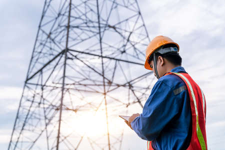 Engineering wear safety clothes working on High-voltage tower, Check the information on taplet.の写真素材
