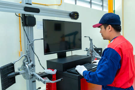Auto mechanic or technician controls a car lift program by computer in car auto repair service...