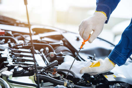 Close up hand auto mechanic check new car engine oil in car service center.の写真素材