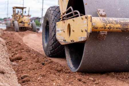 Close up Yellow vibratory soil and Motor Grader Civil compactor working on road construction site, Yellow vibratory soil compactor in road construction siteの写真素材