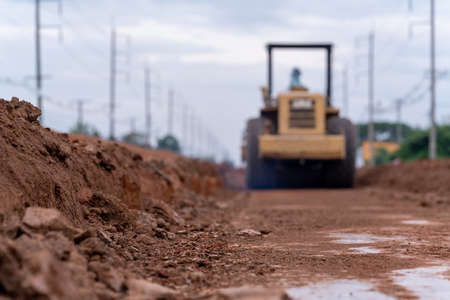 Blurred Yellow vibratory soil compactor working on road construction, Yellow vibratory soil compactor in road construction siteの写真素材