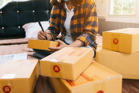 Close up Online shopping young women start small business in a cardboard box at work. The seller prepares the delivery box for the customer, online sales, or ecommerce.の写真素材
