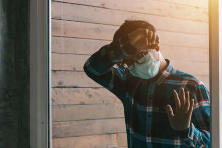 Depressed crying asian business man sad in the mirror with headache. Coronavirus COVID-19 impact on retail businesses shut down causing  business failure and unemployment problem.の写真素材
