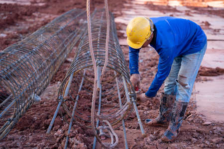 construction worker install a lifting sling which steel mesh to the load while crane is lifting construction siteの写真素材