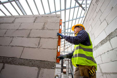 Asain worker using water level meter measuring the wall builder working with autoclaved aerated...