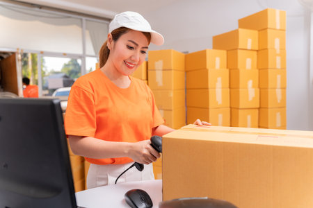 Asian parcel delivery worker in warehouse with barcode scanner.の写真素材