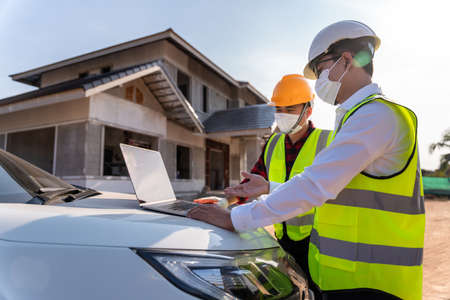Architect and Supervisors using laptop at construction site, House construction ideas during the  outbreak. House builder concept.の写真素材