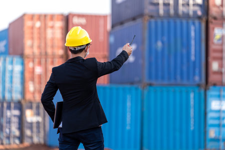 foreman worker use a long distance radio control container cargo harbor to loading containers. Logistics import export shipping concept.の写真素材
