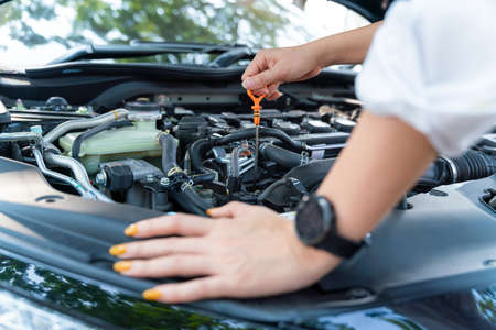 Close up hand of woman check the oil level in car engine.
