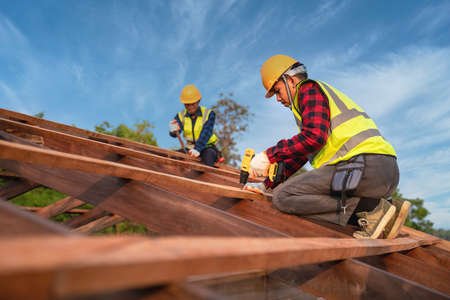 Two construction worker install new roof, Roofing tools, Electric drill used on new roofs of wooden roof structure, Teamwork construction concept.の写真素材