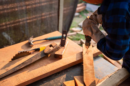 Carpenter drills wood a hole with an electrical drill.の写真素材