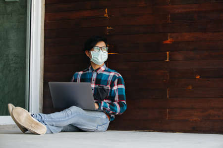 freelance man working jobs wear protective masks sitting stressed from unemployment at home Concept of economic crisis, people unemployment and production of Coronavirus Disease 2019 or COVID-19.の写真素材