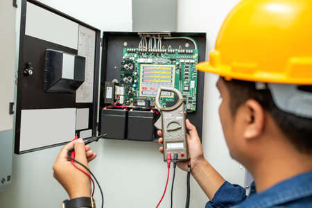 Electrician working use digital clamp meter in hands of electrician, close-up against background of...