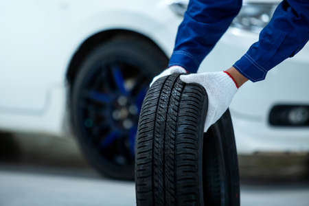 Close up of car mechanic's hand holds a tire, New tires that change tires in the auto repair service...