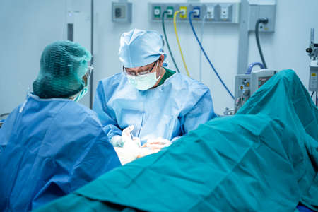 Surgeons and an assistant Hands out Instruments operating the bone in the patient's arm in the operating room. Professional Medical Doctors Performing Surgery, Orthopedic surgeon conceptの写真素材