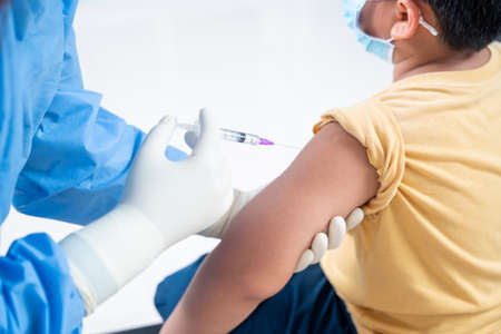 Close up of hand doctor making a vaccination in the shoulder of patient boy or child person, Injection on Arm, coronavirus,covid-19 vaccine disease preparing for human clinical trials vaccination shotの写真素材