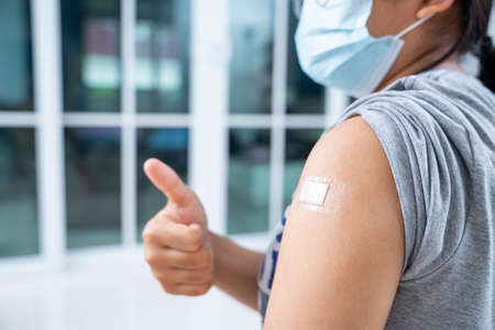 Close up of happy teens girls and wear a mask in the shoulder with plaster on arm after vaccination in hospitalの写真素材