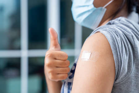 Close up of teens girls and wear a mask in the shoulder with plaster on arm after vaccination in hospitalの写真素材
