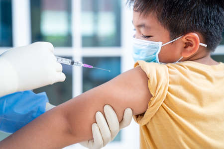 Flu Vaccination Injection on Arm, coronavirus, Doctor making a vaccination in the shoulder of patient boy or child person, covid-19 vaccine disease preparing for human clinical trials vaccination shotの写真素材