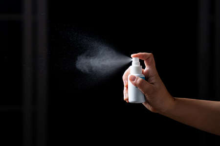 Close up hand of  Portable alcohol spraying antibacterial sanitizing spray bottle disinfecting against COVID-19 spreading. Concept Sanitize surfaces prevention in hospitals and public spaces.の写真素材