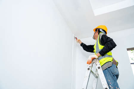 painter man painting the wall in an unfinished building, with paint brush, isolated on big empty...