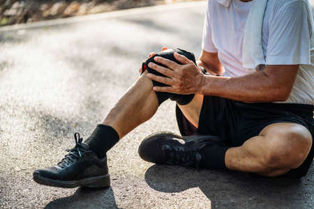 Close up of Senior man suffering with knee pain during workout in the park.の写真素材
